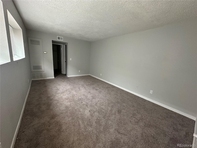 spare room featuring dark colored carpet and a textured ceiling