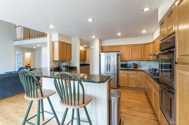 14261 W Evans Cir, Lakewood, CO 80228 - kitchen with appliances with stainless steel finishes, light wood-type flooring, a peninsula, a kitchen bar, and recessed lighting