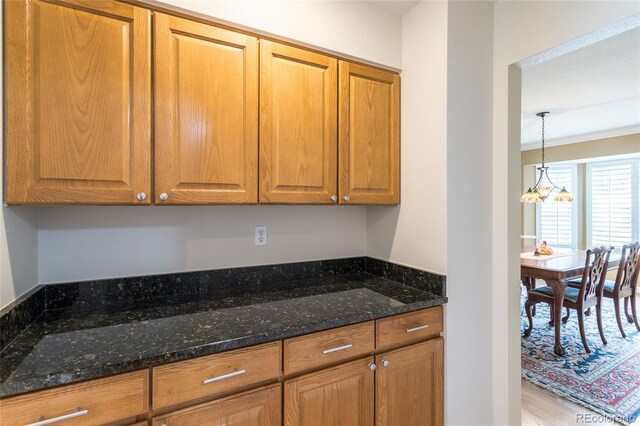 14261 W Evans Cir, Lakewood, CO 80228 - kitchen featuring dark stone countertops, brown cabinetry, light wood-style flooring, and a chandelier