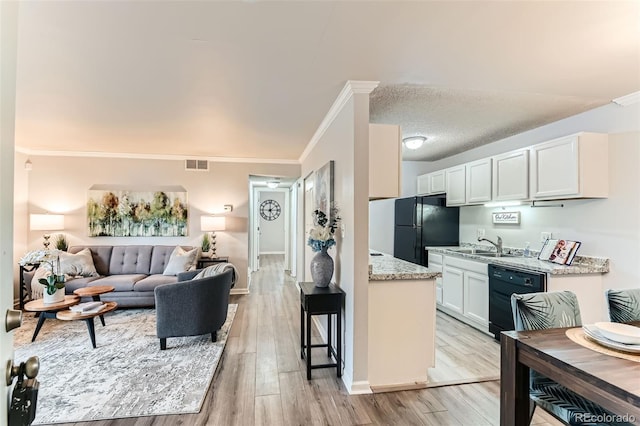 10211 Ura Ln Unit 1-308, Thornton, CO 80260 - kitchen featuring black appliances, open floor plan, crown molding, light wood-style floors, and white cabinets