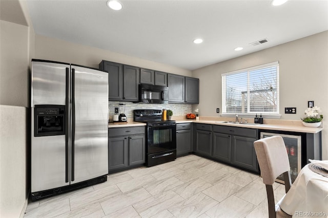 kitchen with gray cabinets, a sink, black appliances, light countertops, and tasteful backsplash