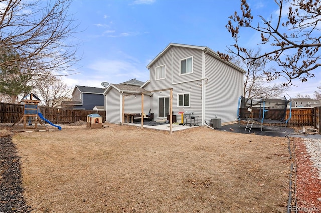 rear view of property with a playground, a trampoline, a patio area, and a fenced backyard