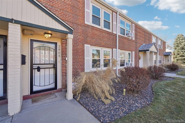 property entrance with brick siding and cooling unit