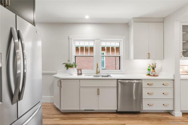 kitchen featuring a sink, appliances with stainless steel finishes, light wood finished floors, and light countertops