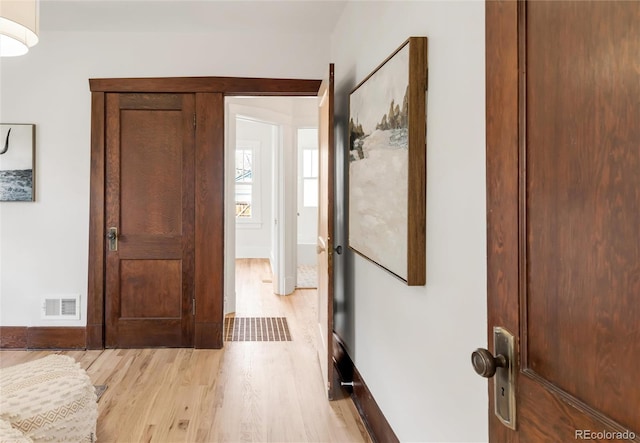 foyer entrance featuring baseboards, visible vents, and light wood-style floors