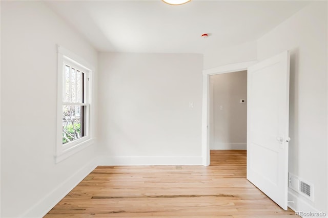unfurnished room featuring baseboards, light wood finished floors, and visible vents