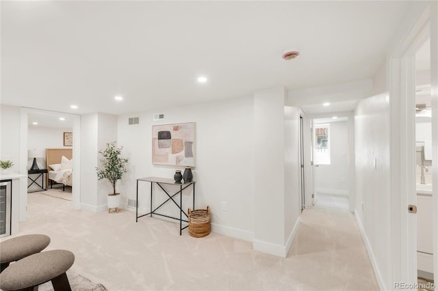 hall featuring light carpet, recessed lighting, and visible vents