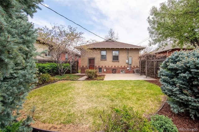 back of house featuring fence, cooling unit, brick siding, a patio area, and a lawn