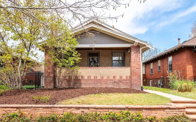 bungalow-style house featuring brick siding, fence, and covered porch