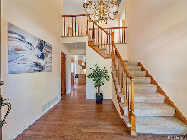 4228 Scenic Village Dr, Evergreen, CO 80439 - staircase with wood finished floors, a chandelier, baseboards, and a high ceiling