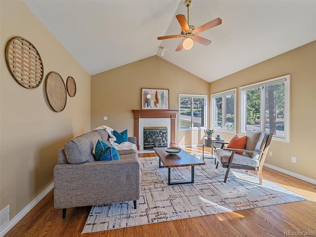 4228 Scenic Village Dr, Evergreen, CO 80439 - living area with wood finished floors, ceiling fan, a tile fireplace, baseboards, and lofted ceiling