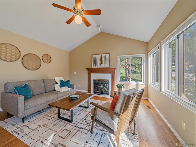 4228 Scenic Village Dr, Evergreen, CO 80439 - living room with light wood finished floors, baseboards, a ceiling fan, vaulted ceiling, and a tiled fireplace