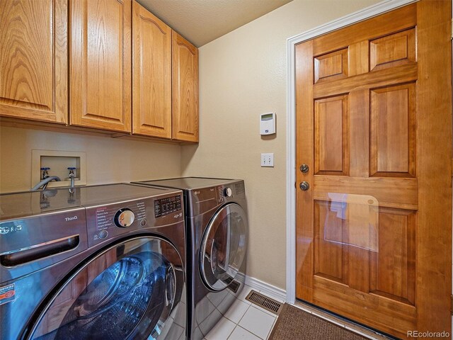 4228 Scenic Village Dr, Evergreen, CO 80439 - laundry area with cabinet space, washing machine and clothes dryer, light tile patterned floors, and baseboards