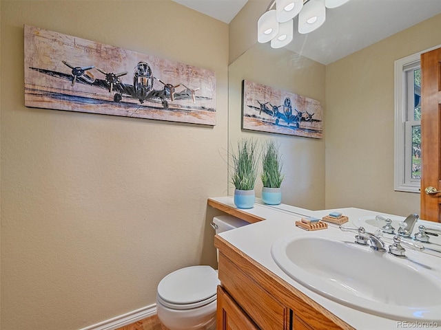 4228 Scenic Village Dr, Evergreen, CO 80439 - half bath featuring vanity, toilet, baseboards, and wood finished floors
