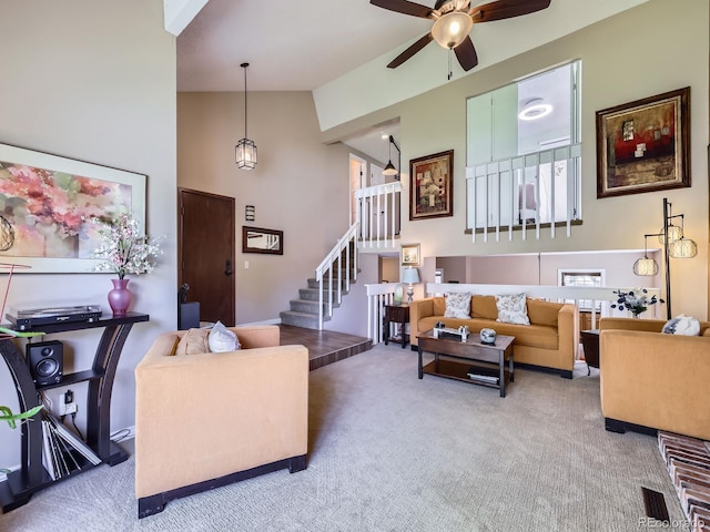 living room with high vaulted ceiling, carpet, ceiling fan, and stairway