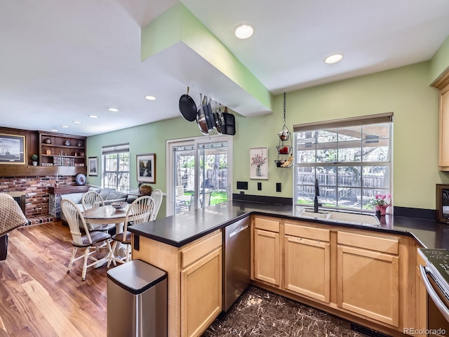 kitchen with a sink, appliances with stainless steel finishes, recessed lighting, light brown cabinetry, and dark countertops