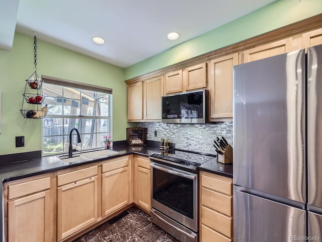 kitchen with appliances with stainless steel finishes, light brown cabinetry, a sink, dark countertops, and recessed lighting