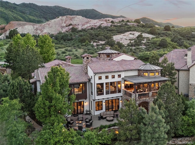 7208 Raphael Ln, Littleton, CO 80125 - back of house at dusk featuring an outdoor hangout area, a patio, a mountain view, and stucco siding