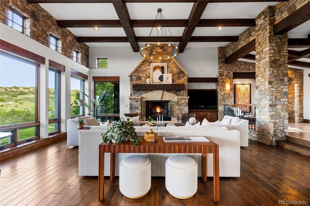 7208 Raphael Ln, Littleton, CO 80125 - living area with beam ceiling, a stone fireplace, dark wood-type flooring, decorative columns, and a towering ceiling