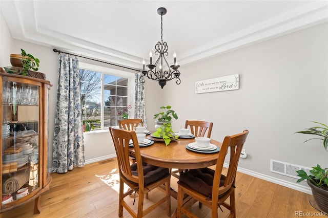 dining area featuring a chandelier, light wood-style floors, and baseboards