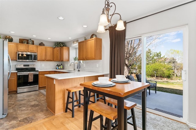 kitchen with stainless steel appliances, a sink, tasteful backsplash, a peninsula, and light countertops