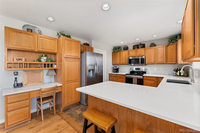 kitchen with stainless steel appliances, a sink, a peninsula, light countertops, and decorative backsplash