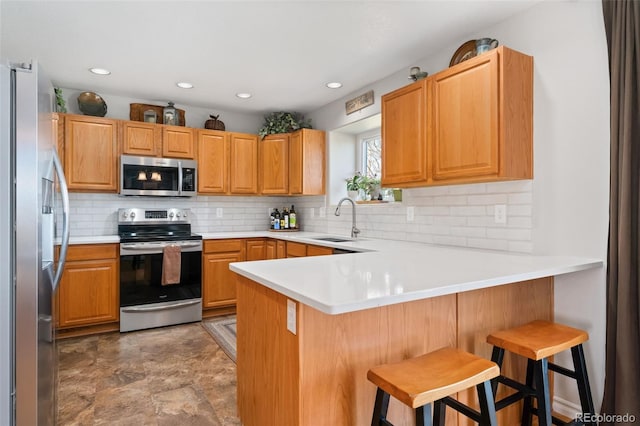 kitchen featuring appliances with stainless steel finishes, a peninsula, decorative backsplash, a sink, and recessed lighting