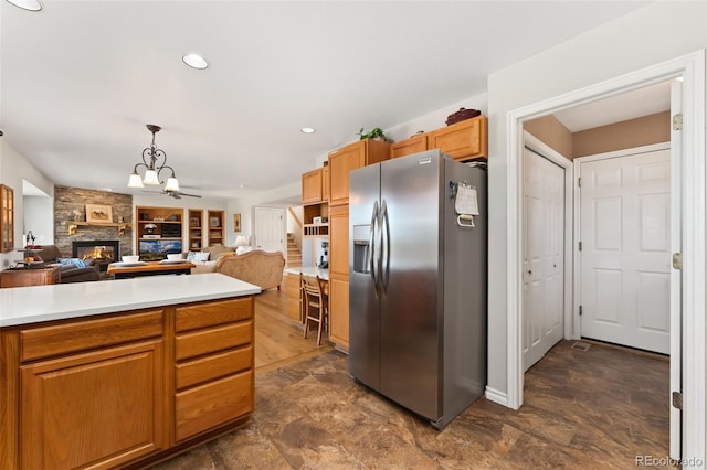 kitchen featuring stainless steel fridge, a chandelier, light countertops, open floor plan, and a fireplace