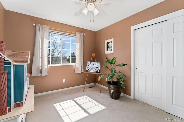 living area with ceiling fan, carpet, and baseboards