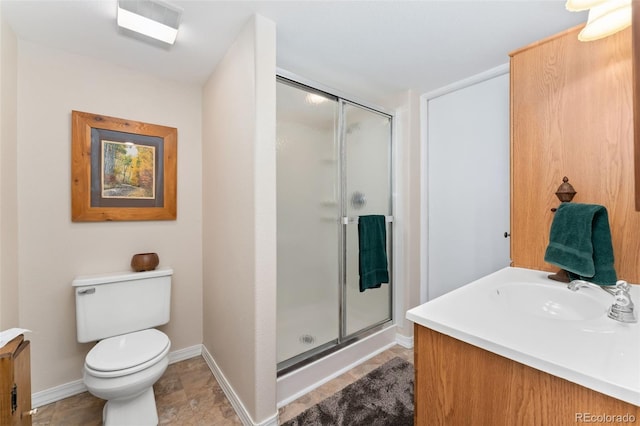 bathroom with a shower stall, vanity, toilet, and baseboards