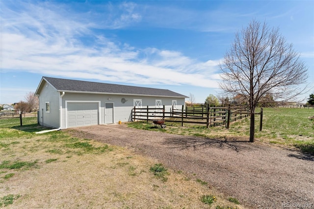 view of outbuilding featuring fence, driveway, an outbuilding, and a garage