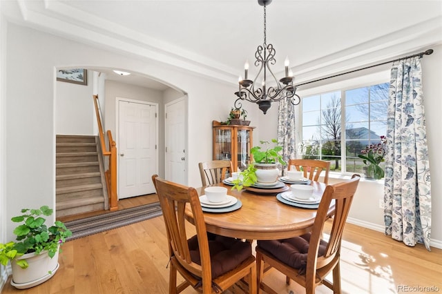 29145 E 160th Ct, Brighton, CO 80603 - dining room with a chandelier, arched walkways, light wood-type flooring, stairs, and baseboards