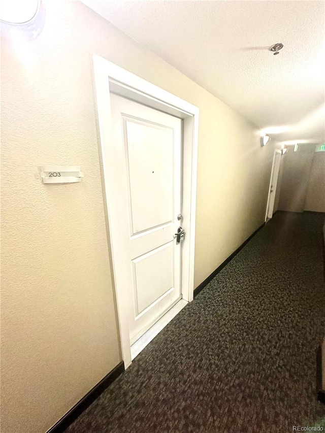 corridor with carpet flooring and a textured ceiling