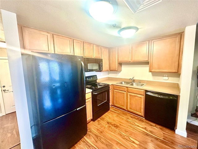 kitchen with sink, a textured ceiling, light brown cabinets, light hardwood / wood-style floors, and black appliances