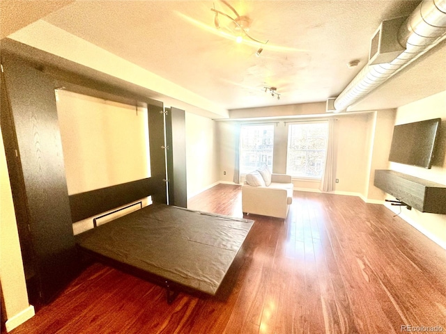 interior space with baseboard heating, a textured ceiling, and hardwood / wood-style flooring