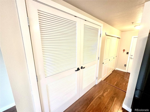 hallway with dark hardwood / wood-style floors and a textured ceiling