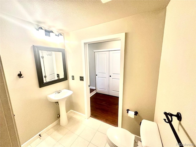 bathroom featuring tile patterned floors, toilet, sink, and a textured ceiling