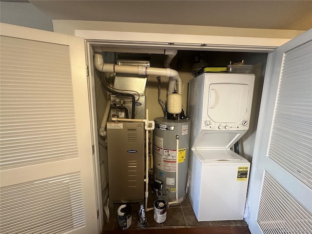 clothes washing area with stacked washer / drying machine, gas water heater, and dark tile patterned floors