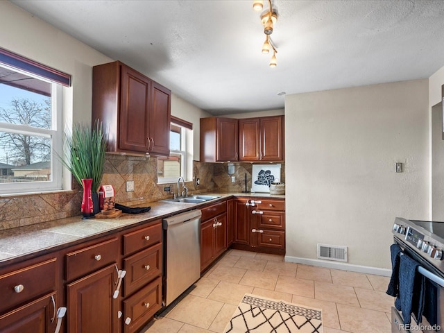 kitchen featuring sink, stainless steel appliances, track lighting, decorative backsplash, and light tile patterned floors