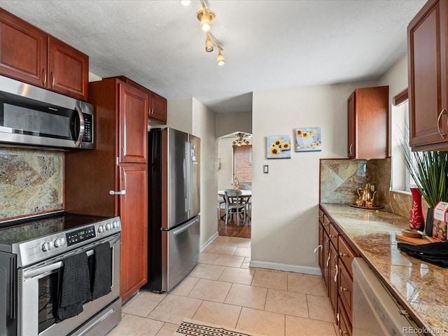 kitchen featuring decorative backsplash, light tile patterned floors, stainless steel appliances, and ceiling fan