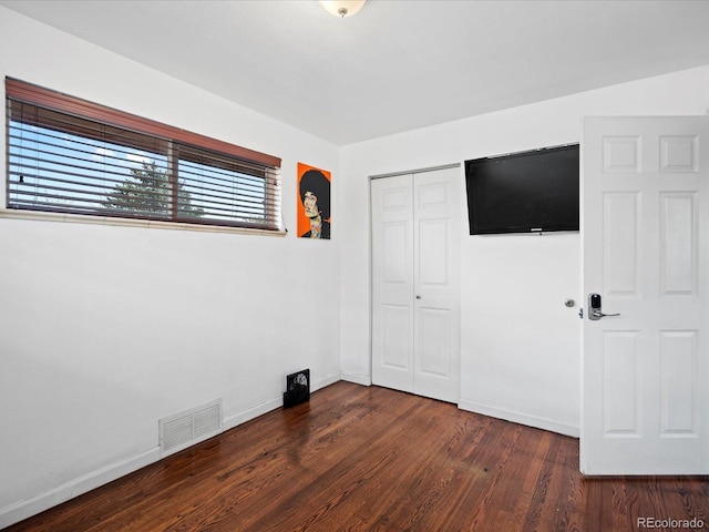 unfurnished bedroom featuring dark hardwood / wood-style floors and a closet