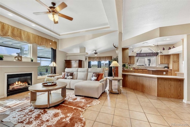 5129 S Tom Bay Rd, Bennett, CO 80102 - living area with a raised ceiling, a glass covered fireplace, ceiling fan, and light tile patterned flooring