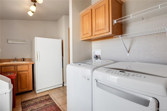 5129 S Tom Bay Rd, Bennett, CO 80102 - laundry area with light tile patterned floors, separate washer and dryer, cabinet space, and a textured wall