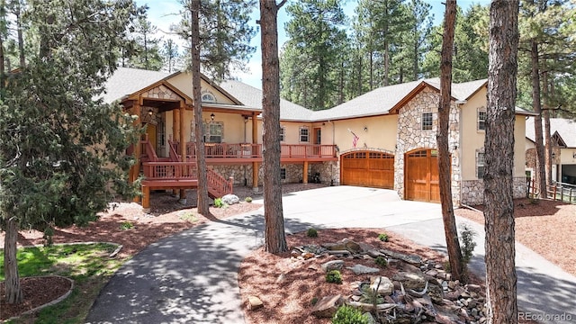 view of front of house featuring stone siding, concrete driveway, stucco siding, covered porch, and a garage