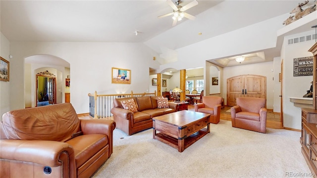 living area featuring arched walkways, ceiling fan, lofted ceiling, light carpet, and baseboards