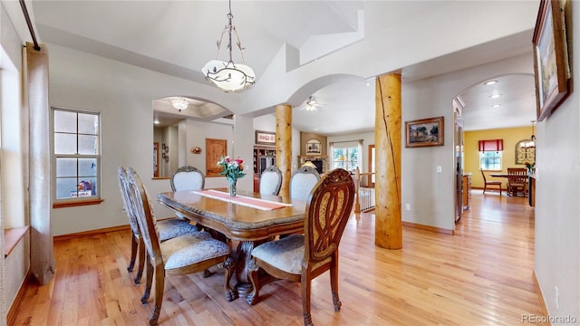 dining space with light wood-style flooring, arched walkways, plenty of natural light, ceiling fan, and lofted ceiling