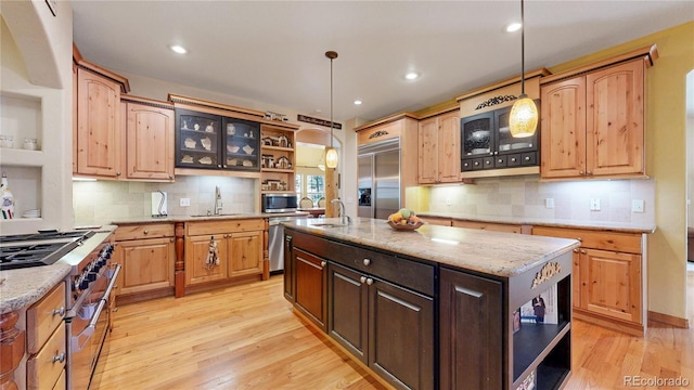 kitchen featuring open shelves, premium appliances, light wood-style flooring, a sink, and backsplash