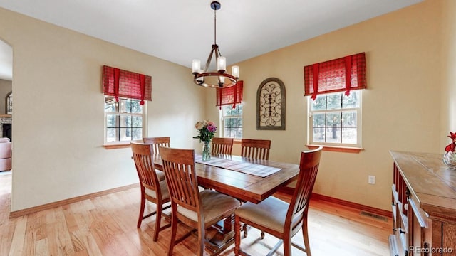 dining space with healthy amount of natural light, light wood-style floors, and a chandelier
