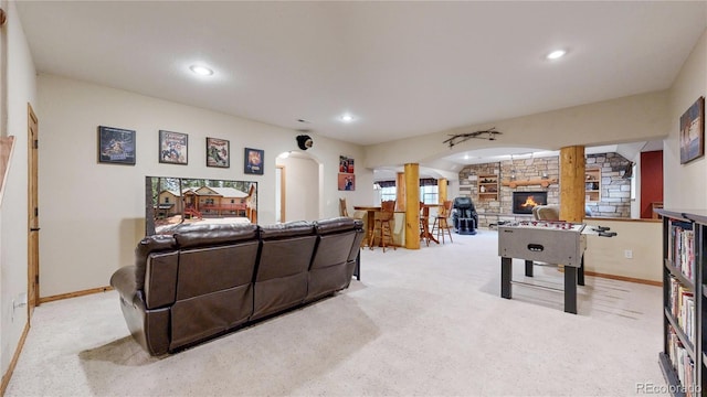 recreation room with carpet flooring, arched walkways, baseboards, recessed lighting, and a stone fireplace