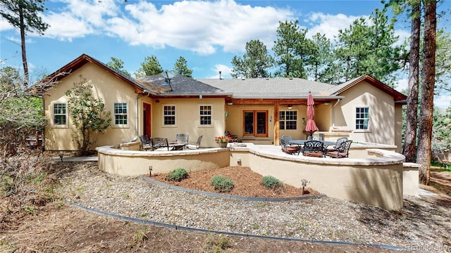 back of house with an outdoor fire pit, a patio, stucco siding, and a shingled roof